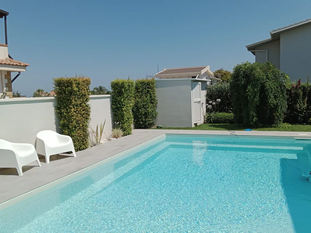 La piscina con le siepi sempreverdi e il prato intorno