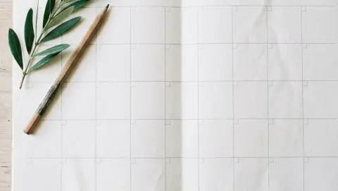 Un planning di carta a caselle vuote, con un rametto verde e una matita